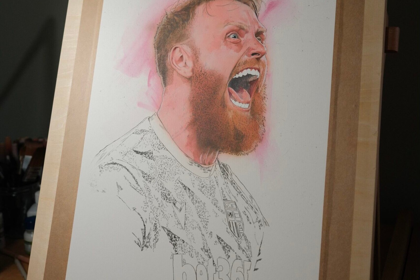 Work-in-progress portrait of Stoke City goalkeeper Viktor Johansson on a drawing board, with the face partly painted and the shirt still in linework.