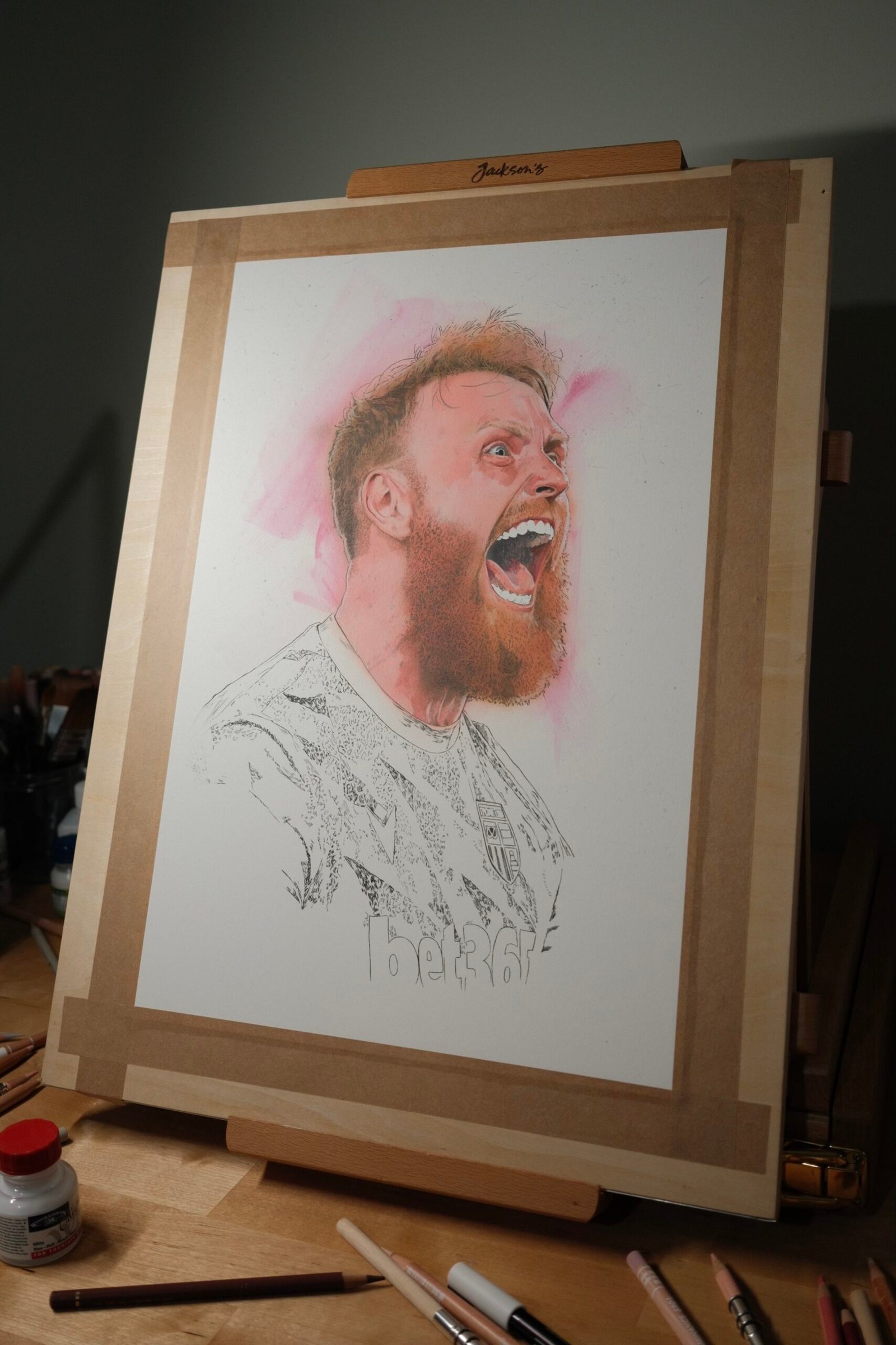 Work-in-progress portrait of Stoke City goalkeeper Viktor Johansson on a drawing board, with the face partly painted and the shirt still in linework.